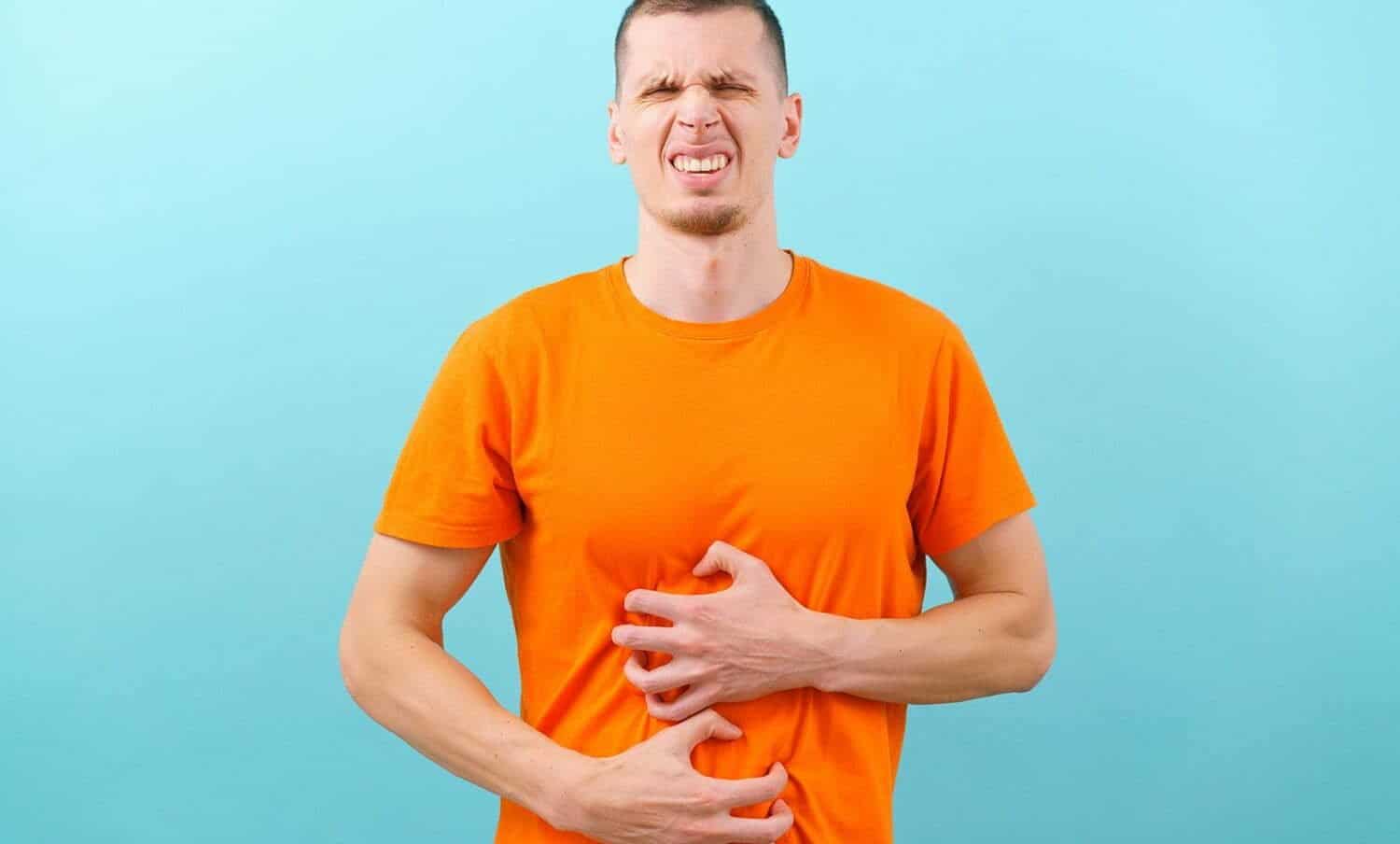 hombre con gesto de malestar, se agarra su est&oacute;mago por dolor, a causa de gases abdominales