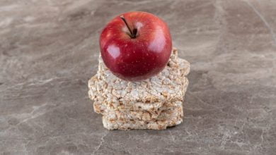 Manzana sobre pila de tortas de arroz inflado en la superficie de m&aacute;rmol