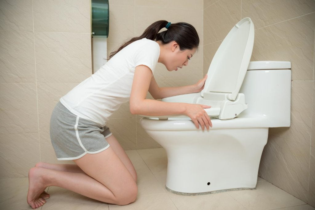 mujer con n&aacute;useas y v&oacute;mito en un sanitario