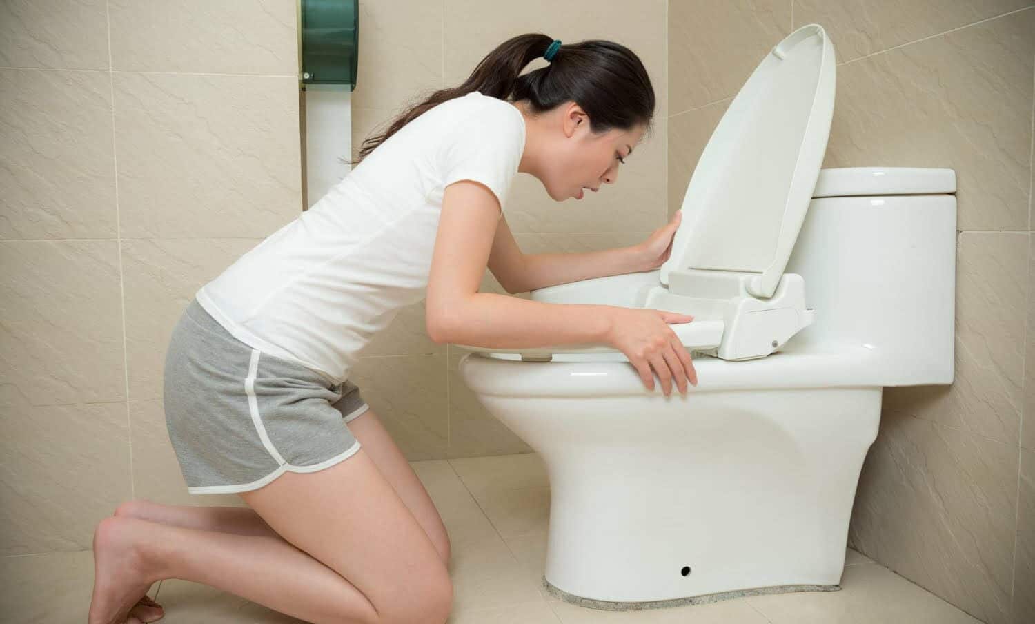 mujer con n&aacute;useas y v&oacute;mito en un sanitario