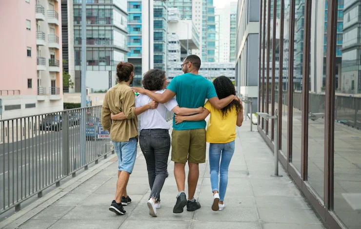 cuatro personas caminan abrazadas por un puente relaciones / feliz / final de la vida, amigos