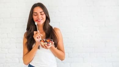Mujer feliz comiendo una taza de frutas, sin fatiga ni cansancio / embarazo