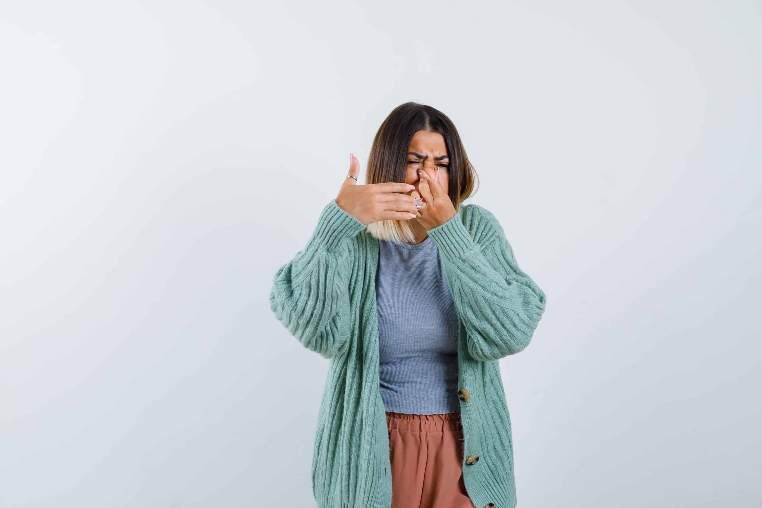 Mujer tap&aacute;ndose la nariz por el mal olor de la ropa /malos olores olor a sudor