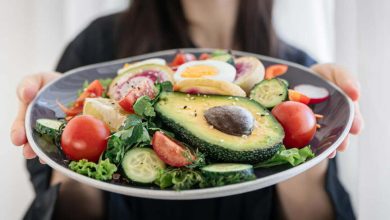 Ensalada apetitosa con verduras frescas y huevos en un plato en manos femeninas / perder peso