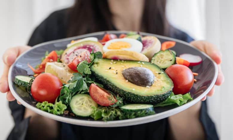Ensalada apetitosa con verduras frescas y huevos en un plato en manos femeninas / perder peso