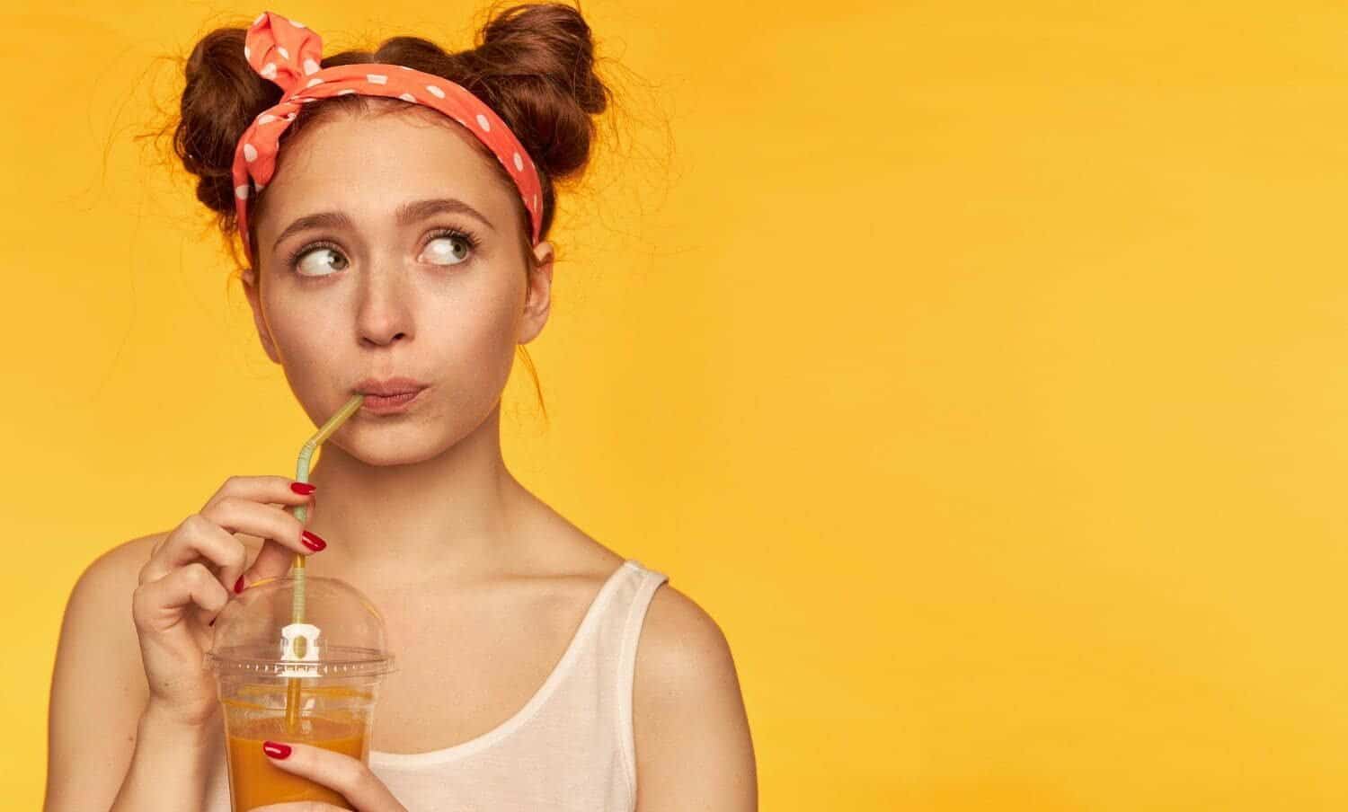 mujer joven tomando un jugo por la dieta l&iacute;quida