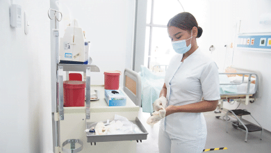 Enfermera coloc&aacute;ndose guantes en cuarto de paciente / profesionales en enfermer&iacute;a