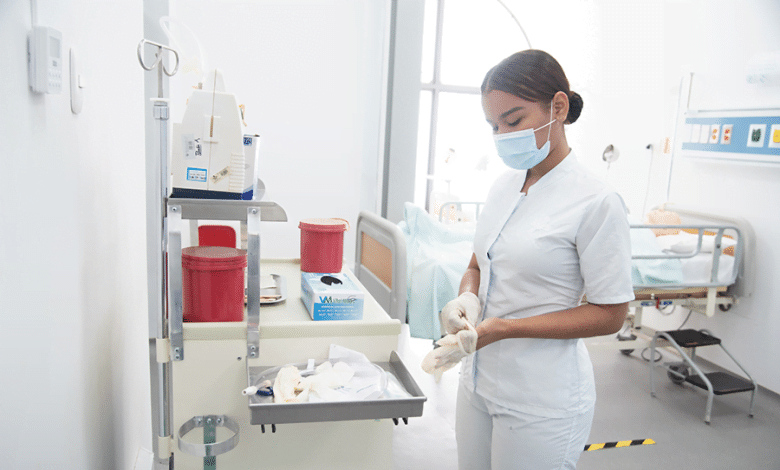 Enfermera coloc&aacute;ndose guantes en cuarto de paciente / profesionales en enfermer&iacute;a