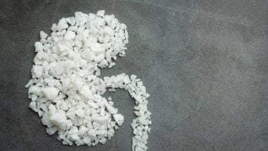 granos grandes de sal formando un ri&ntilde;&oacute;n sobre piso oscuro, como alegor&iacute;a a los c&aacute;lculos renales