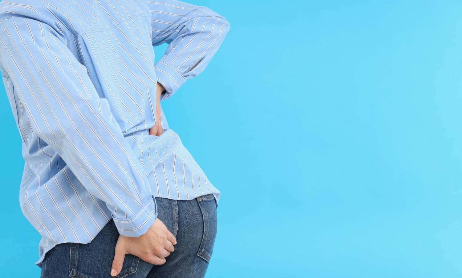 Persona toc&aacute;ndose el trasero, por dolor de hemorroides