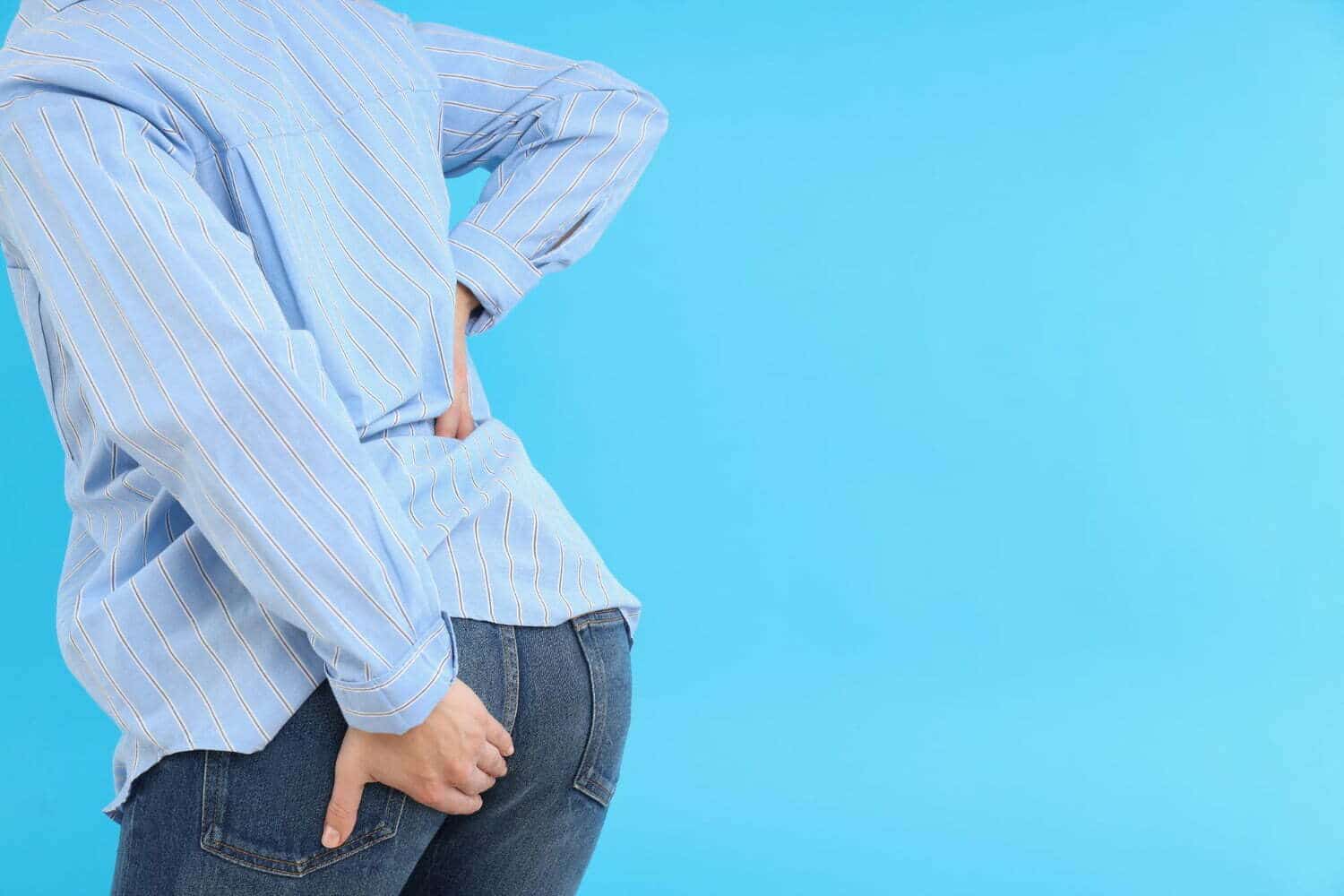 Persona toc&aacute;ndose el trasero, por dolor de hemorroides