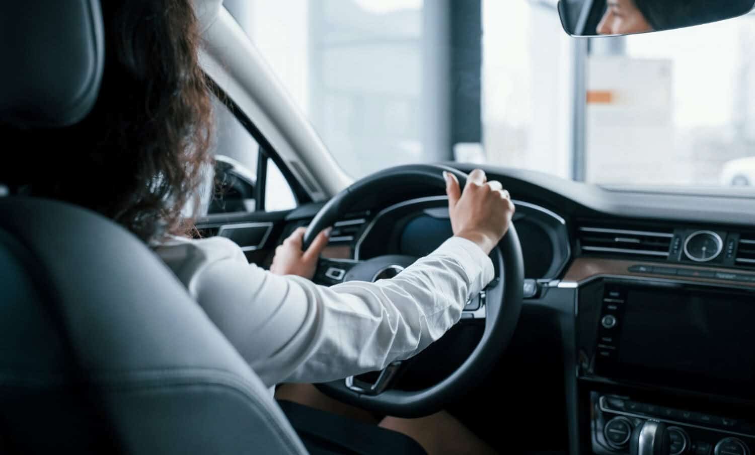 Manos en el volante. bella empresaria probando su nuevo coche en el sal&oacute;n del autom&oacute;vil / zapatos que no debes usar si vas a manejar / conducir / parquear / licencias de conducci&oacute;n / microsue&ntilde;os