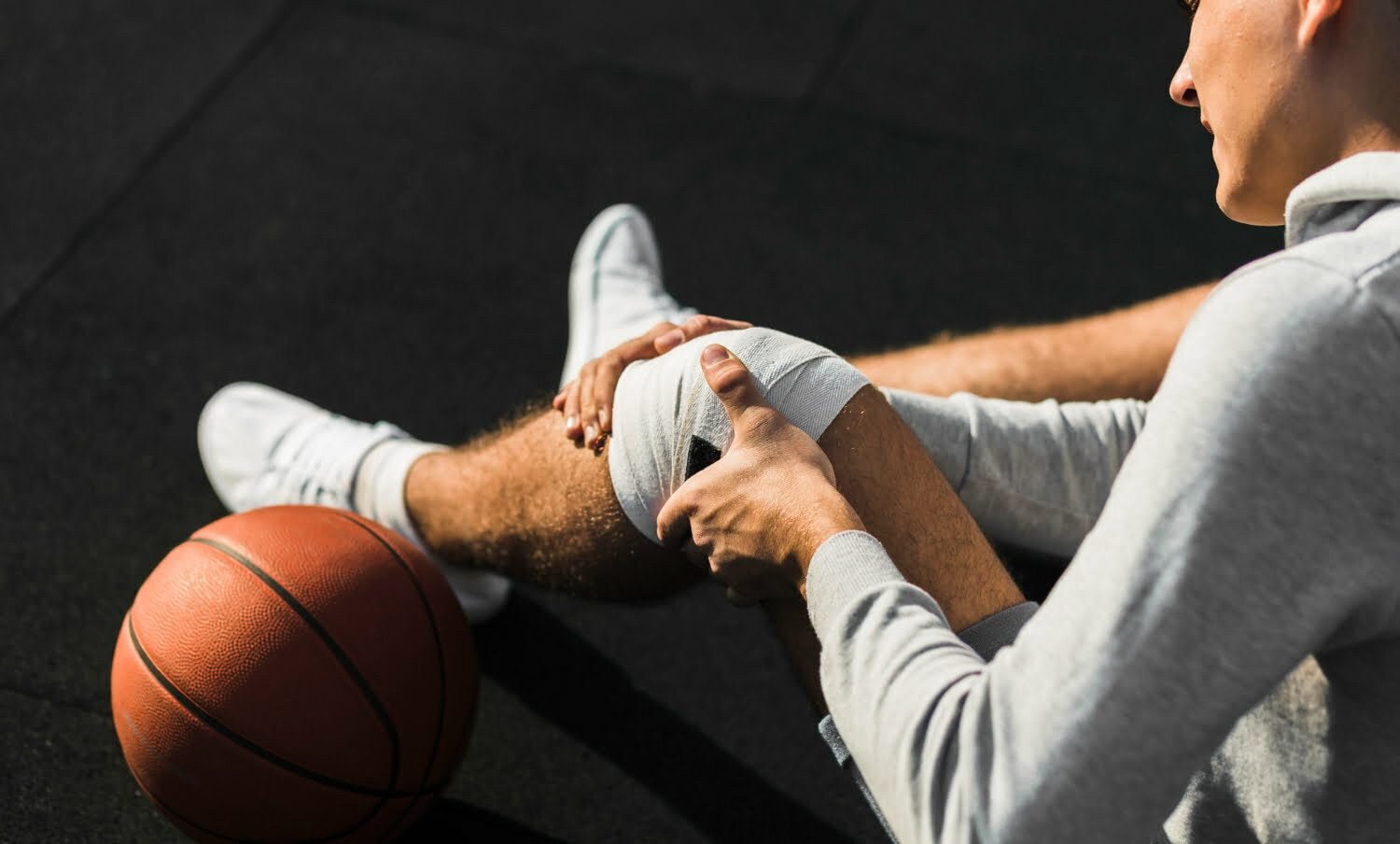 Jugador de baloncesto aplicando vendaje en la rodilla por lesión.