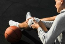 Jugador de baloncesto aplicando vendaje en la rodilla por lesión.