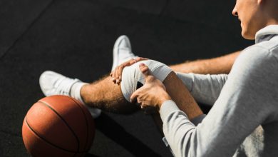 Jugador de baloncesto aplicando vendaje en la rodilla por lesi&oacute;n.