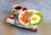 desayuno con huevos fritos y pan en forma de coraz&oacute;n y verduras frescas | alimentos que debes evitar en el desayuno