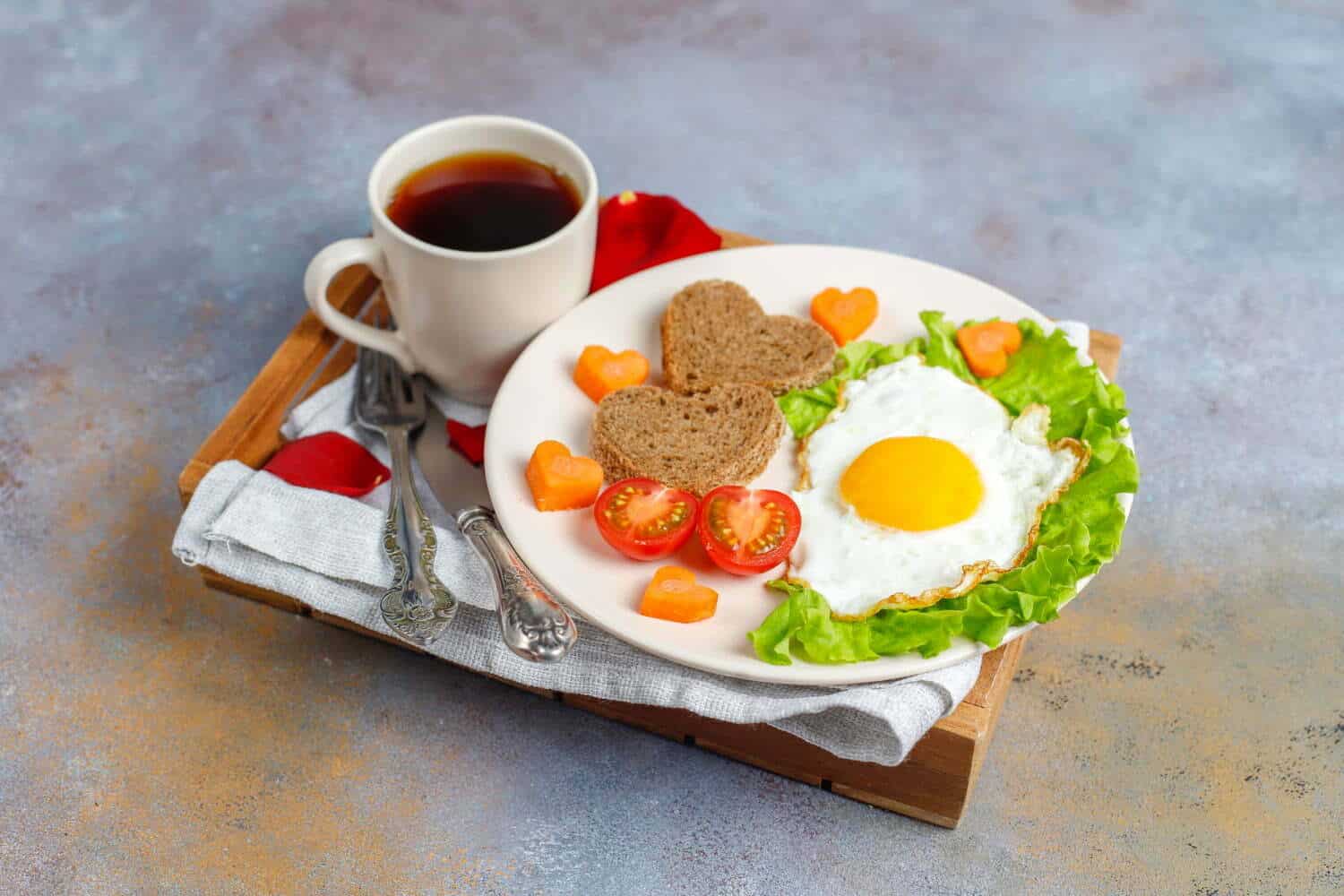 desayuno con huevos fritos y pan en forma de coraz&oacute;n y verduras frescas | alimentos que debes evitar en el desayuno
