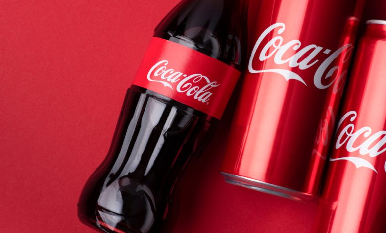 Una botella y dos latas de Coca Cola sobre un fondo rojo | Coca-Cola pirata