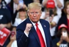 Donald Trump hace gestos con el puño lleno de confianza en el escenario en un mitin de campaña en el Giant Center