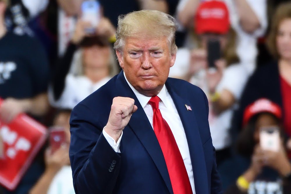 Donald Trump hace gestos con el puño lleno de confianza en el escenario en un mitin de campaña en el Giant Center