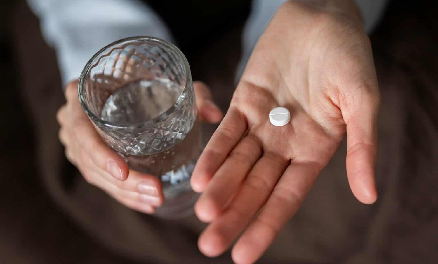 Cierra las manos sosteniendo la pastilla y el vaso / efecto placebo