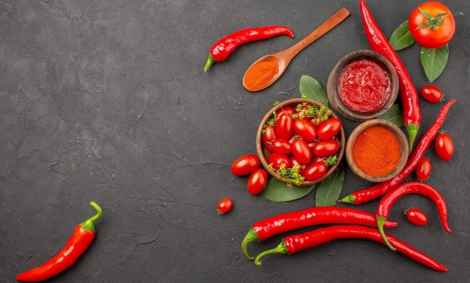 Vista superior de un taz&oacute;n de tomates cherry pimientos rojos picantes una cuchara de madera / el picante | picante en el desayuno