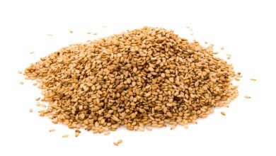 Semillas de s&eacute;samo doradas sobre fondo blanco