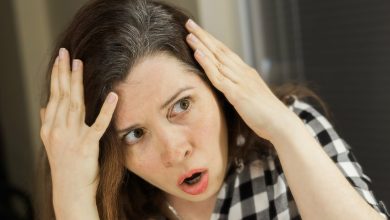 Mujer con cara de sorpresa por encontrarse canas en su cabello
