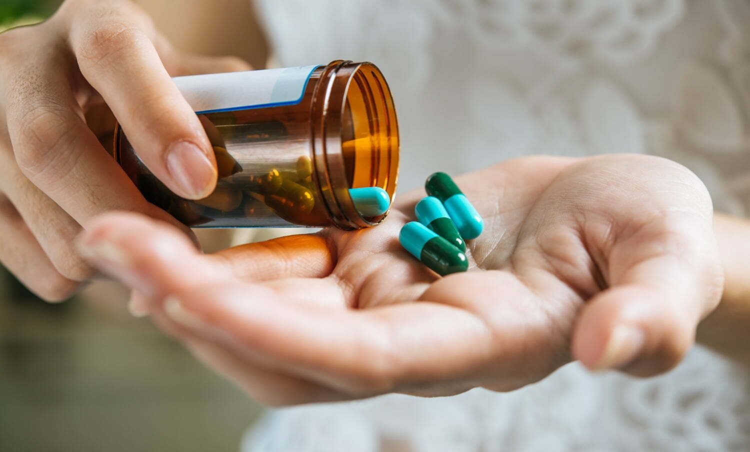 Mano de mujer vierte las pastillas de la medicina fuera de la botella / ibuprofeno y paracetamol