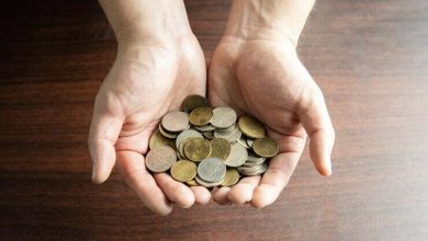 Mano mostrando moneda colombianas sobre un fondo de madera