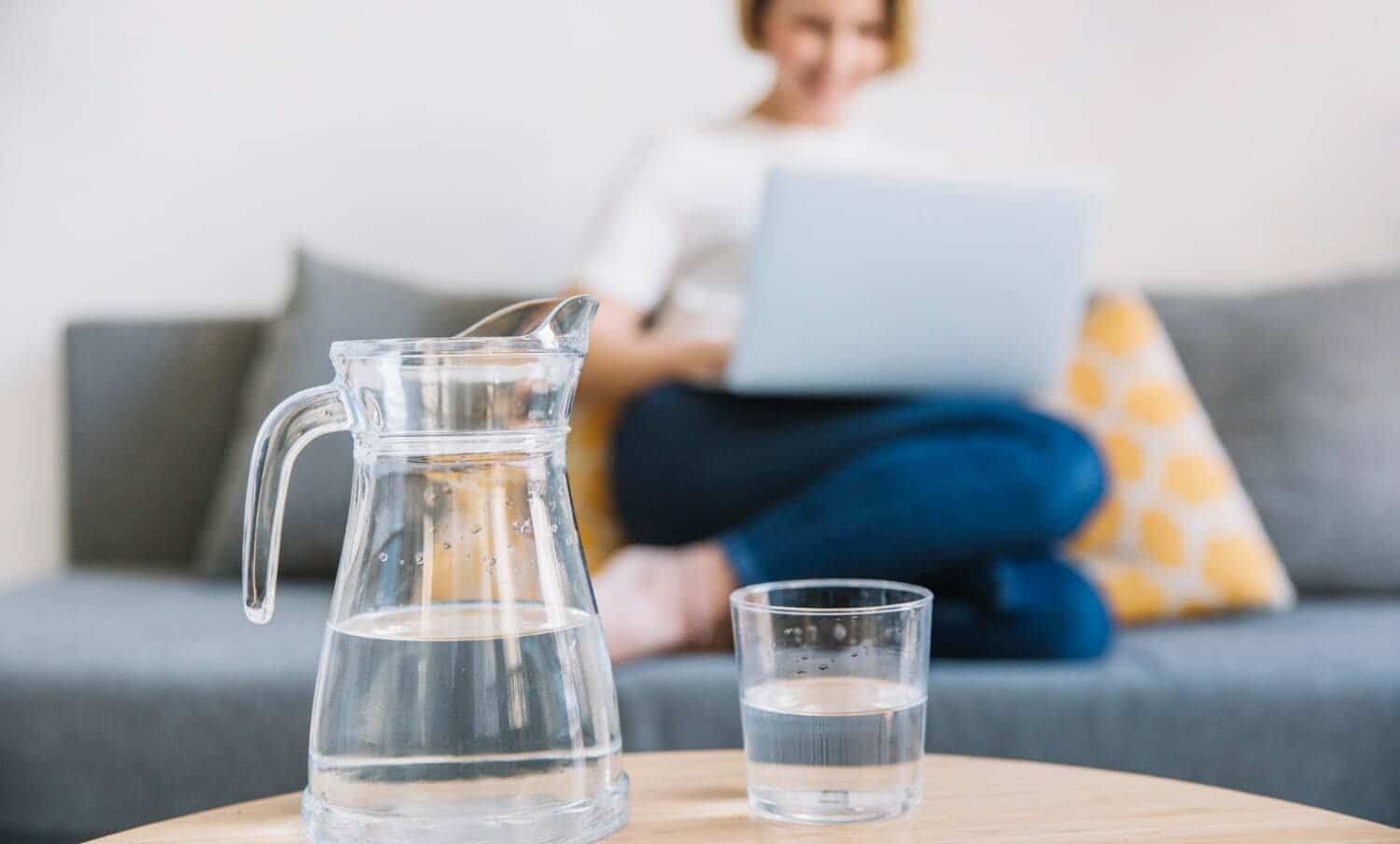 Jarra y vaso de agua cerca de la mujer / sentir mucha sed