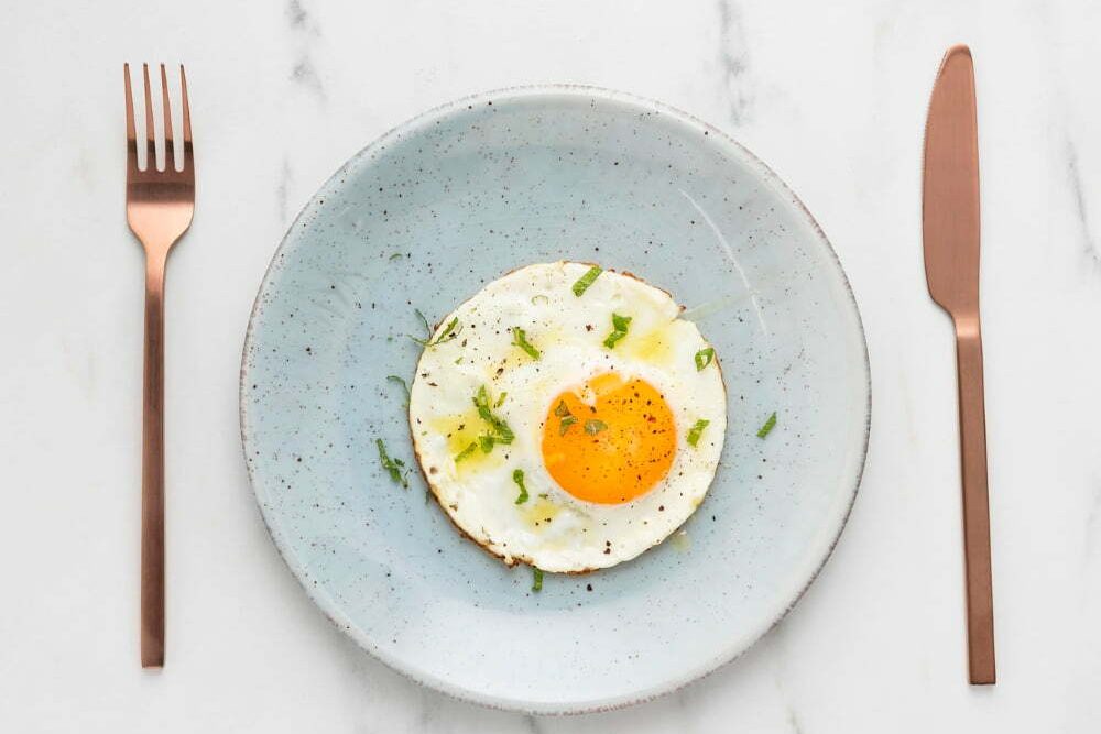 un huevo sobre un plato, y cubiertos, bueno para el colesterol