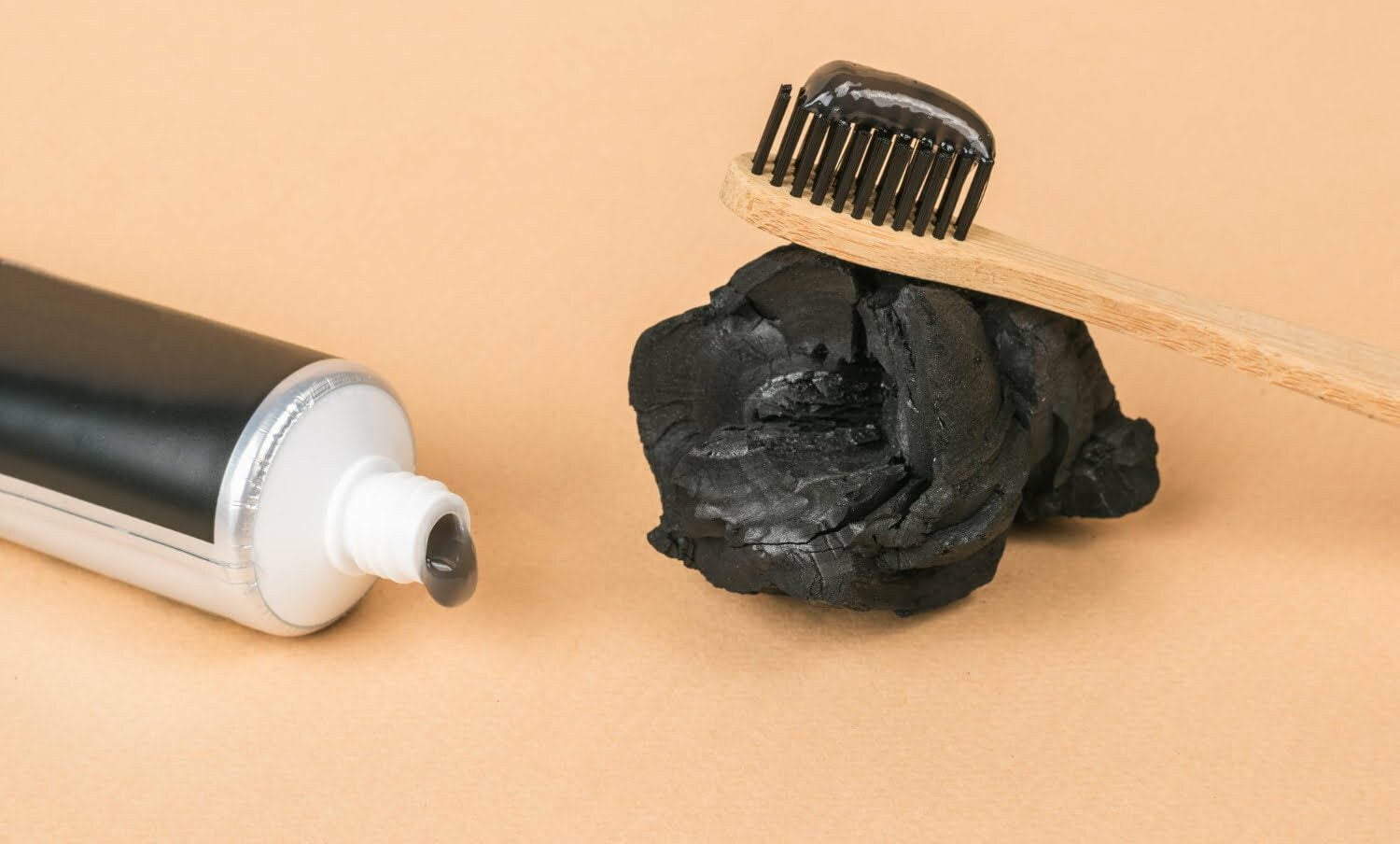 Un tubo de pasta de dientes con la adición de carbón y un cepillo de dientes con pasta dental de carbón activado