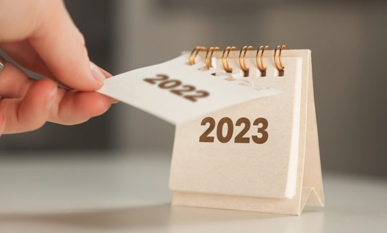 la mano de una mujer da vuelta una hoja de calendario. cambio de año de 2022 a 2023. / Feliz año
