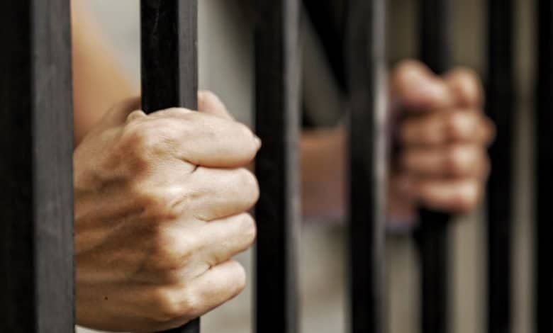 manos de prisioneros con barras de metal negro / La Modelo / primera l&iacute;nea