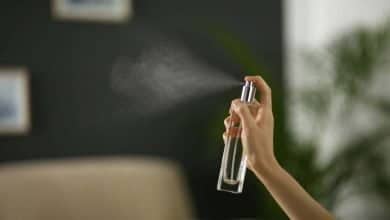 Una mujer rociando un refrescante de aire en casa, cerca. / buen olor