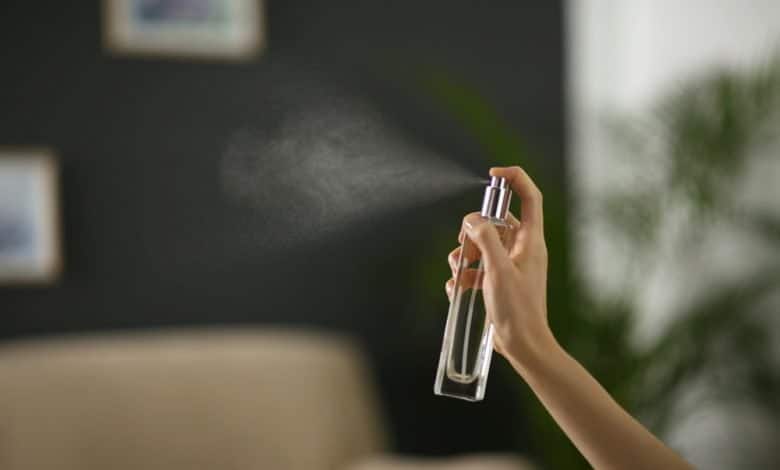 Una mujer rociando un refrescante de aire en casa, cerca. / buen olor