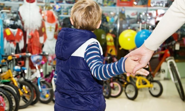 Mamá sosteniendo firmemente al bebé de la mano en una tienda de juguetes / comprar juguetes / Navidad