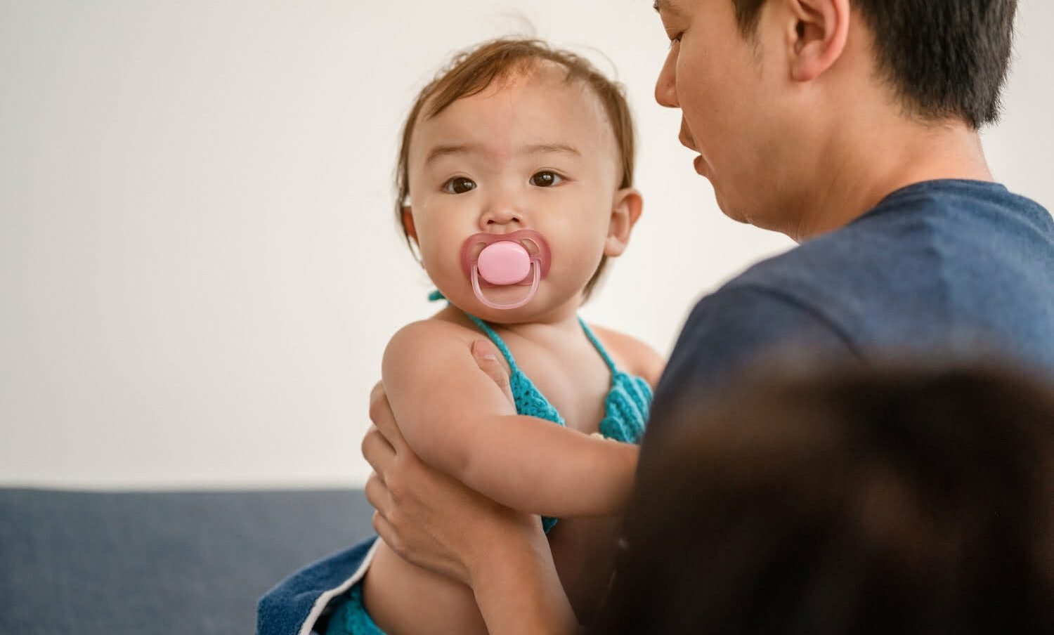 Un papá sosteniendo a su bebé que tiene un chupo en la boca - cuota alimentaria
