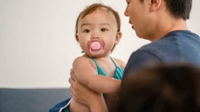 Un pap&aacute; sosteniendo a su beb&eacute; que tiene un chupo en la boca - cuota alimentaria