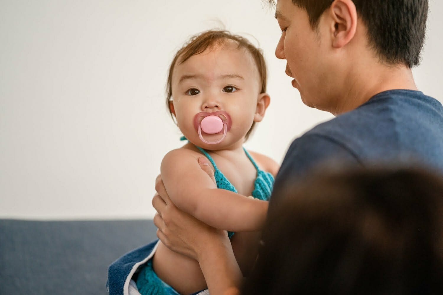 Un papá sosteniendo a su bebé que tiene un chupo en la boca - cuota alimentaria