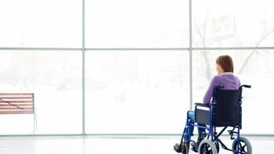 Mujer en silla de ruedas, por esclerosis múltiple, mirando por la ventana.