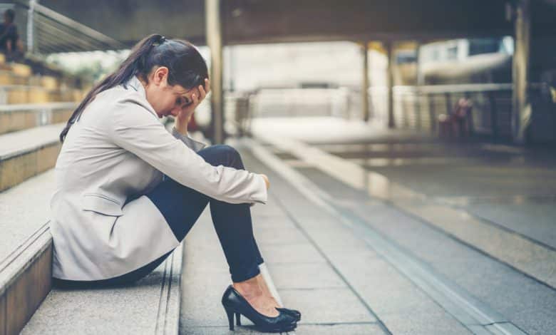Mujer empresaria estresada en el trabajo mientras se sienta al aire libre en las escaleras / estr&eacute;s laboral / agotamiento emocional / rumia mental / alzheimer