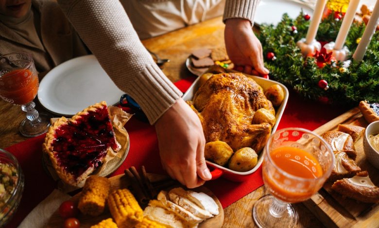 joven poniendo un plato con pavo caliente asado en la mesa de la cena de vacaciones / intoxicaciones por alimentos / &eacute;poca decembrina