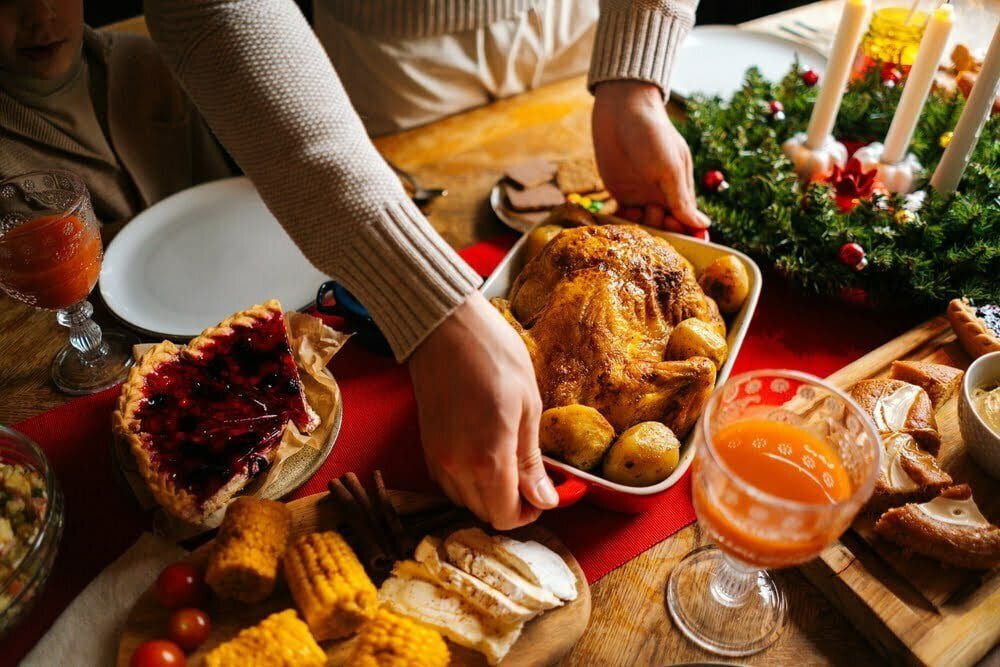 joven poniendo un plato con pavo caliente asado en la mesa de la cena de vacaciones / intoxicaciones por alimentos / &eacute;poca decembrina