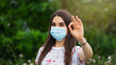 mujer con m&aacute;scara protectora y mostrando signo ok tapabocas