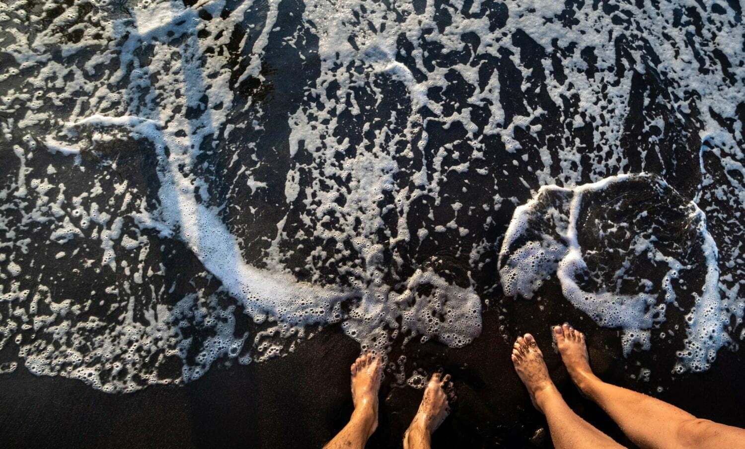 foto de los pies de dos personas en la orilla del mar, haciendo alusión a la talasoterapia