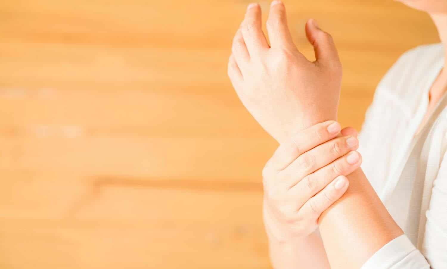 mujer sosteniendo su mu&ntilde;eca s&iacute;ndrome de office sintom&aacute;tico / t&uacute;nel carpiano