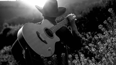 un joven vaquero con su guitarra en el campo / John Rivera
