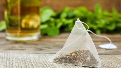 Bolsa de t&eacute; sobre el fondo de la menta y la taza / bolsitas de t&eacute;